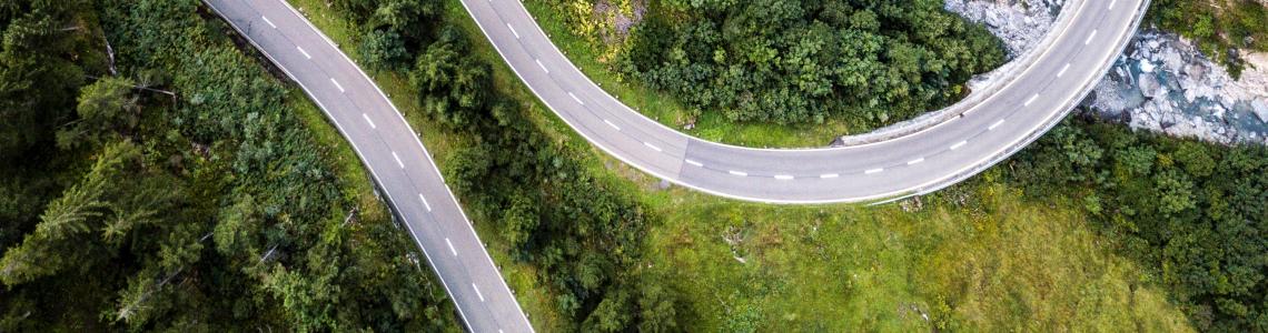 Aerial view over mountain road going through forest landscape