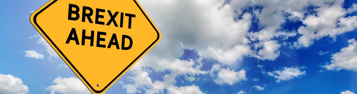 Background of blue sky with cumulus clouds and yellow road sign with text Brexit Ahead