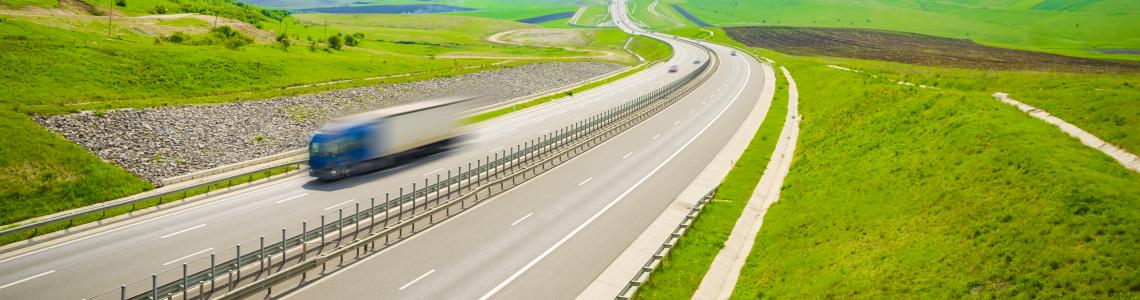 truck on highway surrounded by green landscape