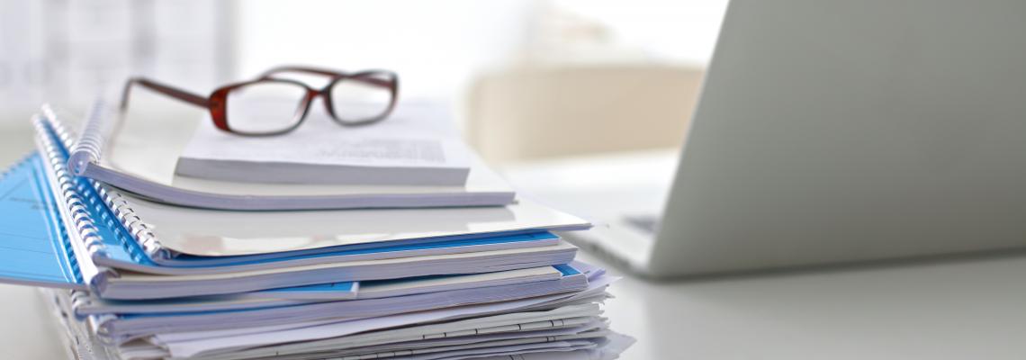 Laptop with stack of folders on table white background