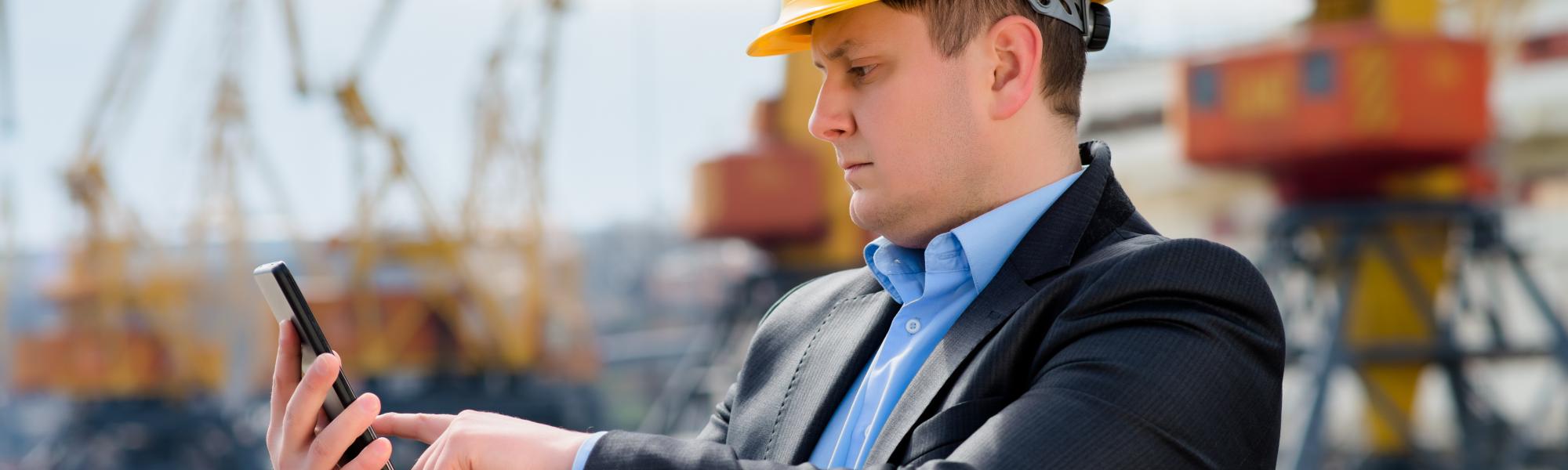 man checking smart phone wearing hard hat