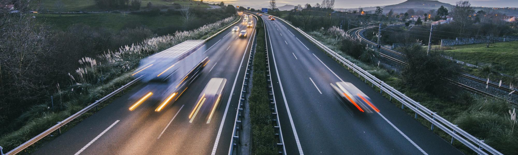 vehicles speeding along highway at dusk