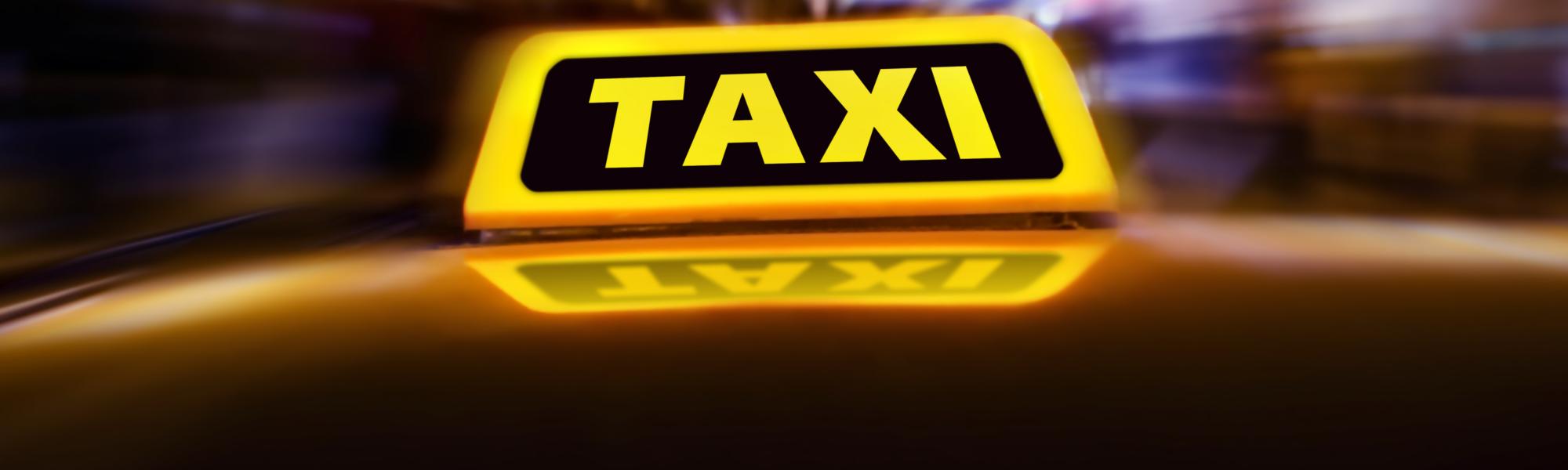 Taxi_sign_on_the_roof_of_car_on_the_street_at_night