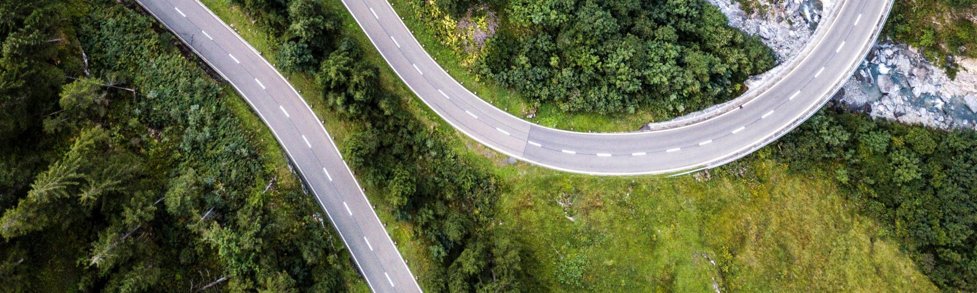 Aerial view over mountain road going through forest landscape