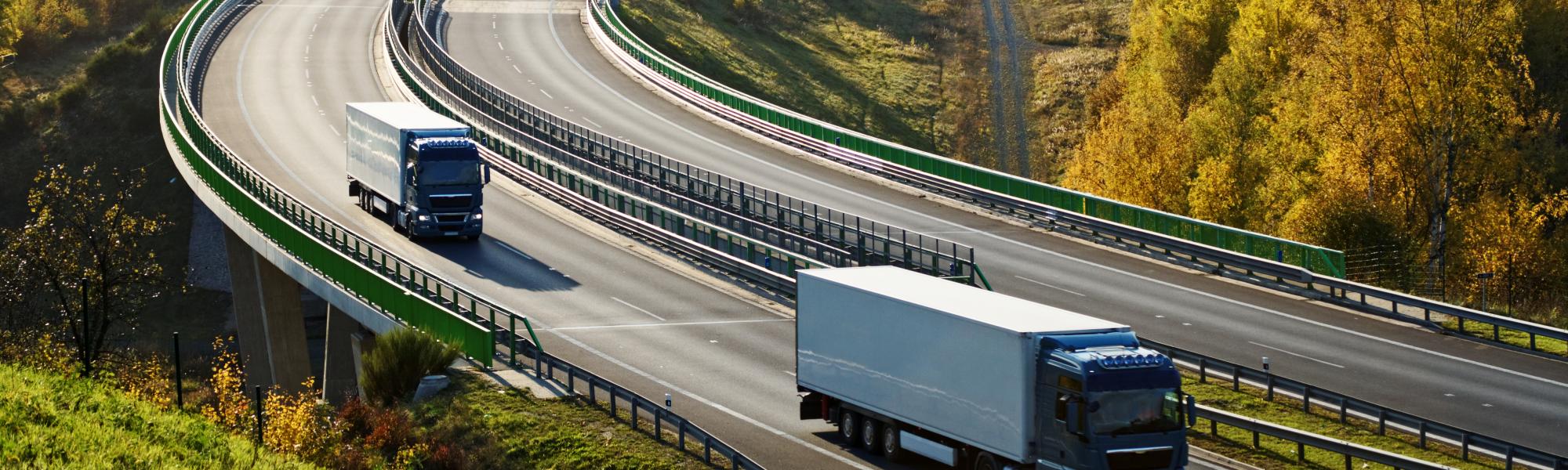 Trucks on a highway in green landscape