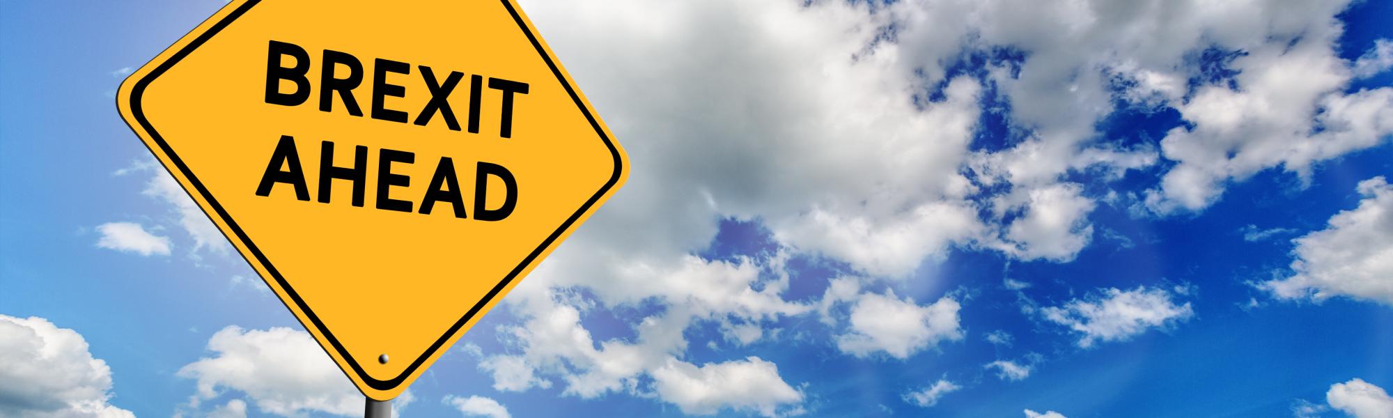 Background of blue sky with cumulus clouds and yellow road sign with text Brexit Ahead