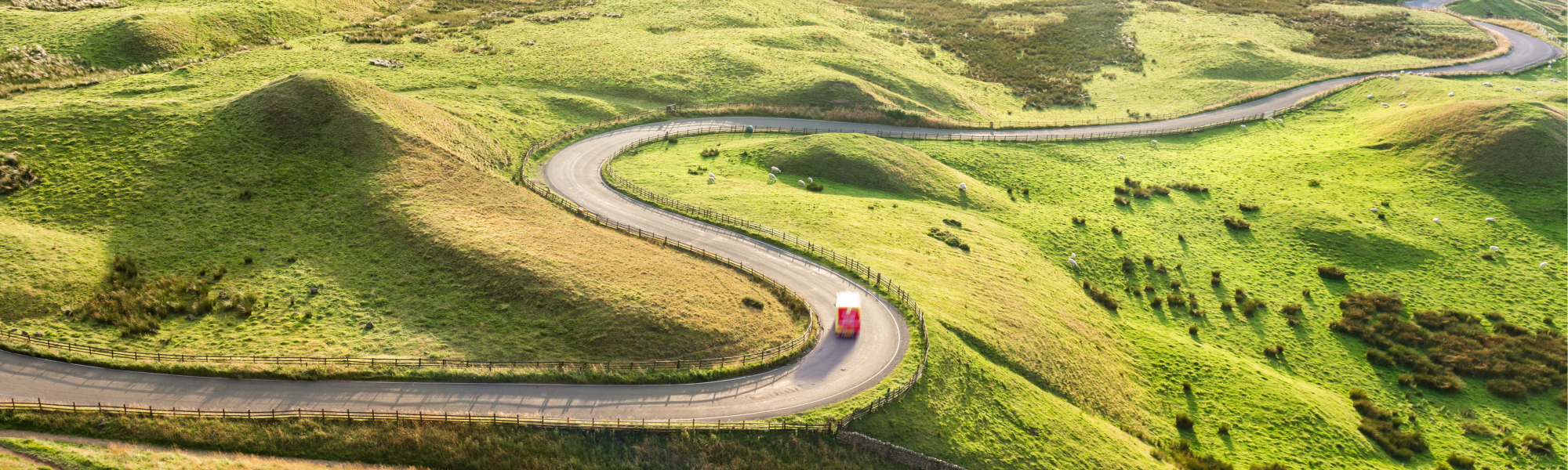 Red Truck on Serpentine Road Among Green Landscape