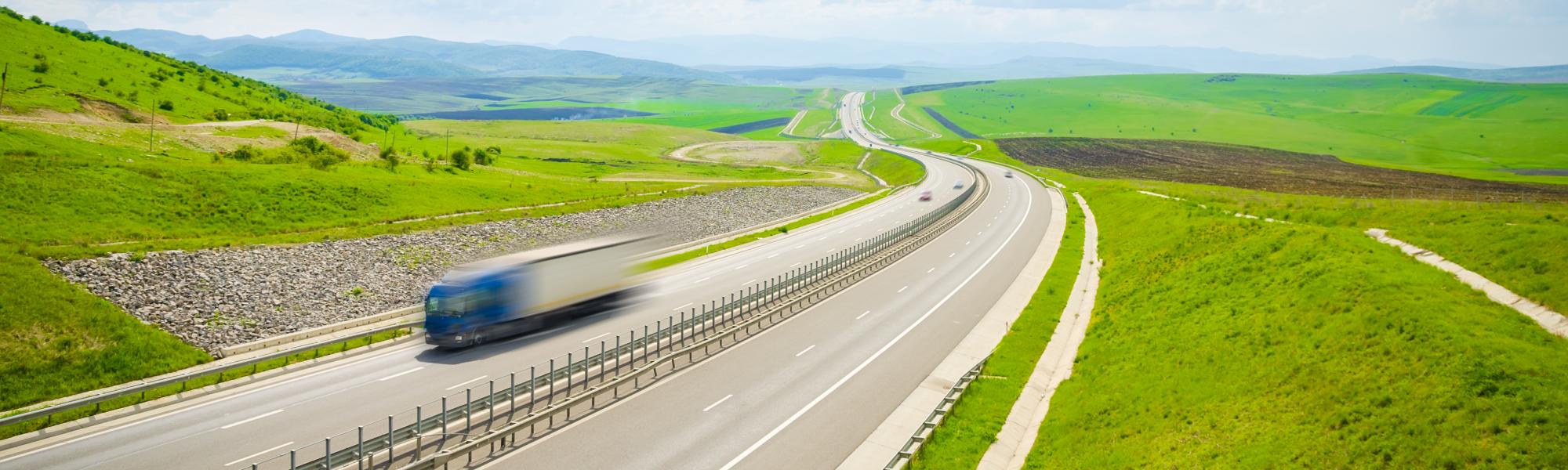 fast truck on a highway over the green hills on a sunny summer day