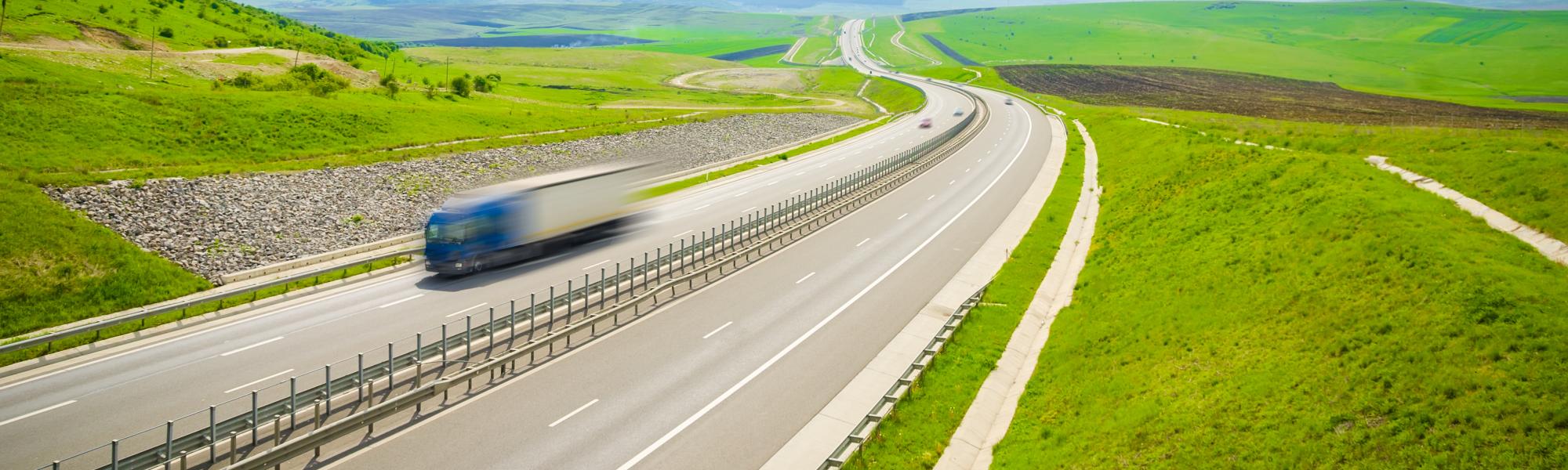 truck on highway surrounded by green landscape